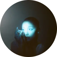 Picture of the singer Ariana Grande clasping her hands, with a blue light highlighting her face.